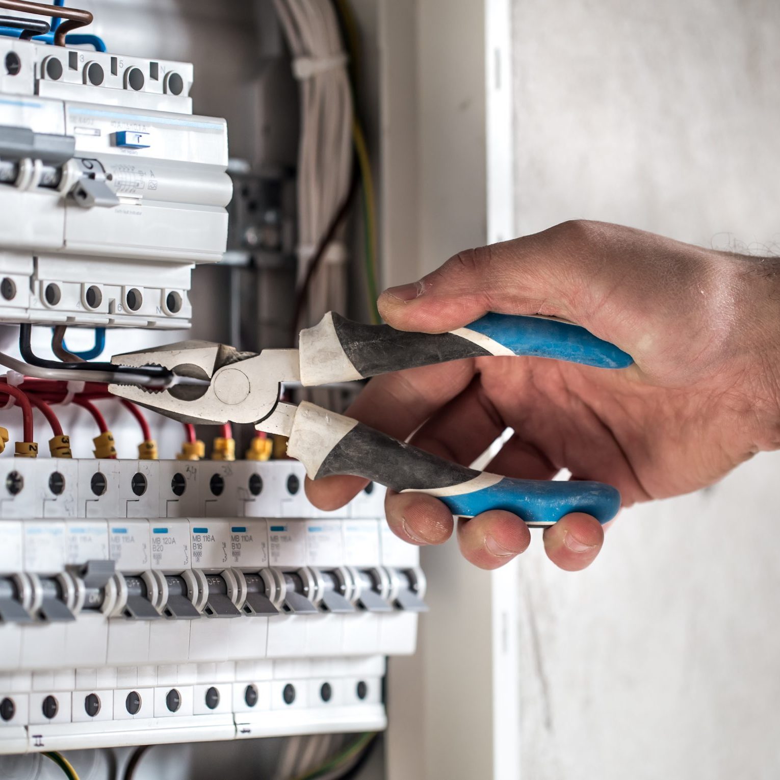Man, an electrical technician working in a switchboard with fuses. Installation and connection of electrical equipment. Close up. Man, an electrical technician working in a switchboard with fuses. Installation and connection of electrical equipment. Professional with tools in hand. concept of complex work, space for text.
