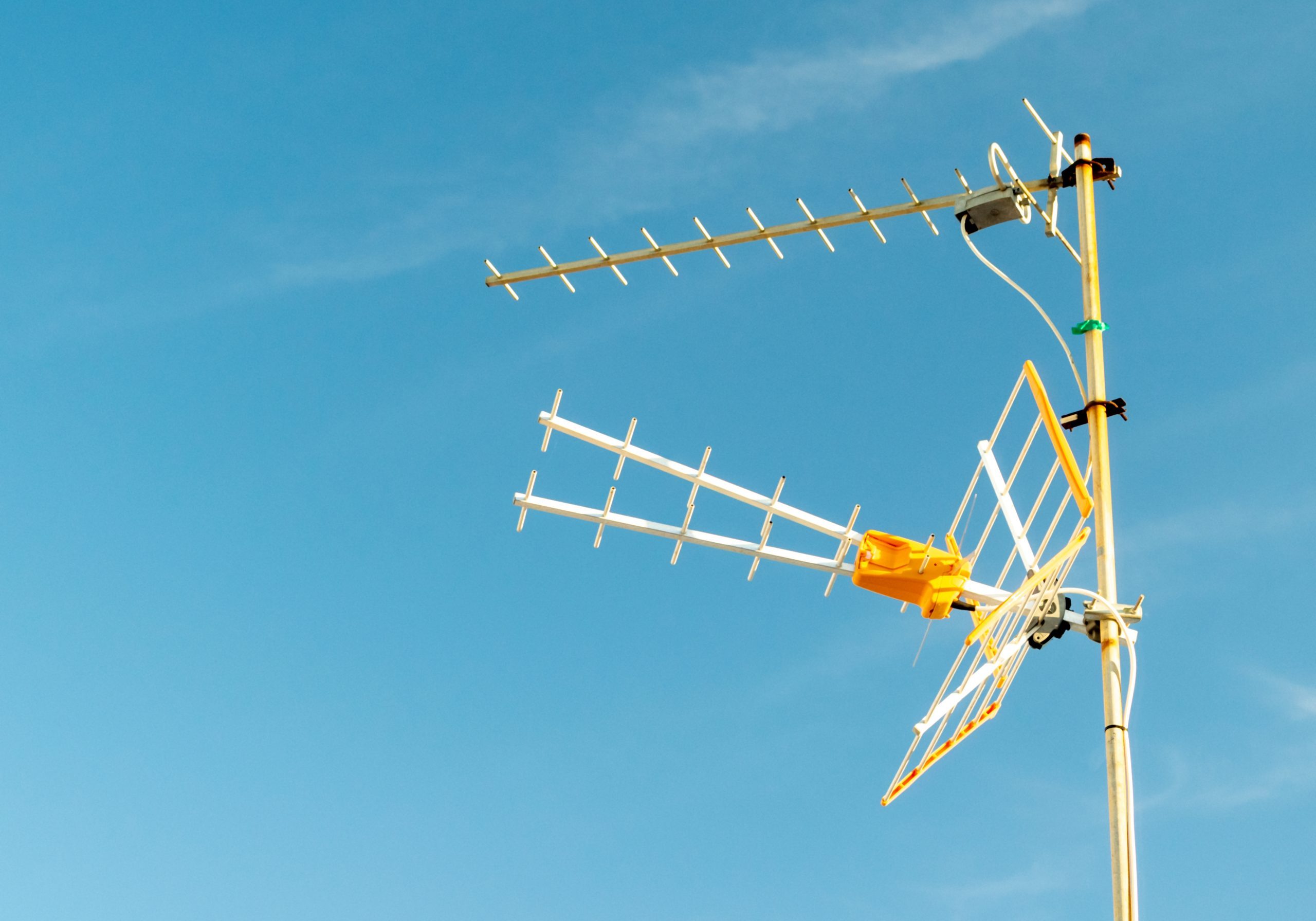 A low angle shot of a television antenna captured on a sunny day with a clear sky