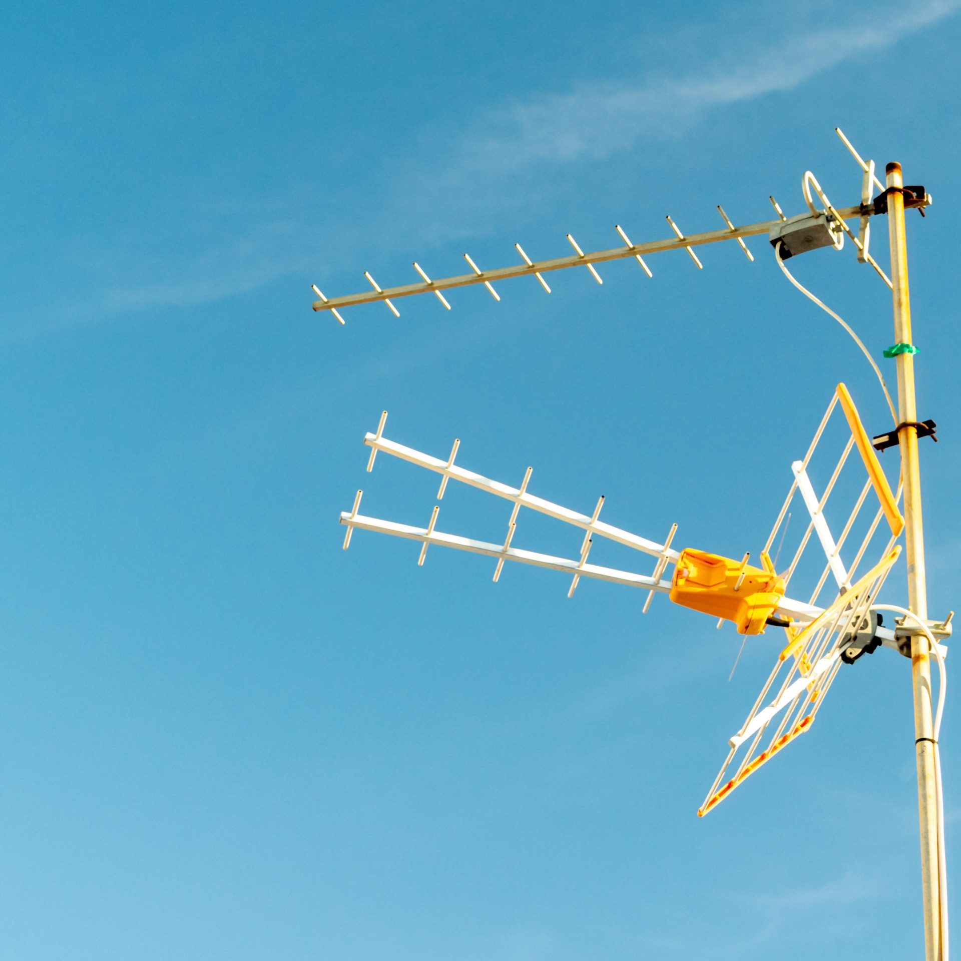 Low angle shot of a television antenna captured on a sunny day with a clear sky A low angle shot of a television antenna captured on a sunny day with a clear sky