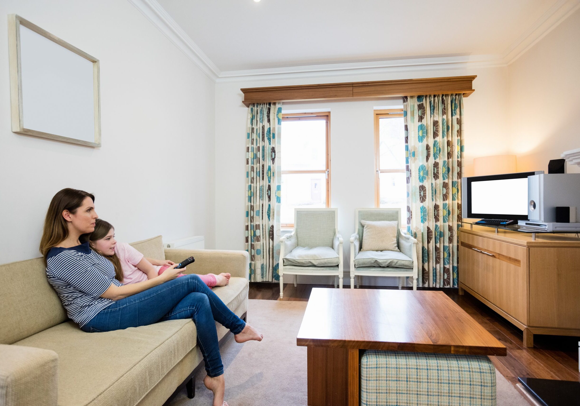 Mother and daughter watching tv in living room at home